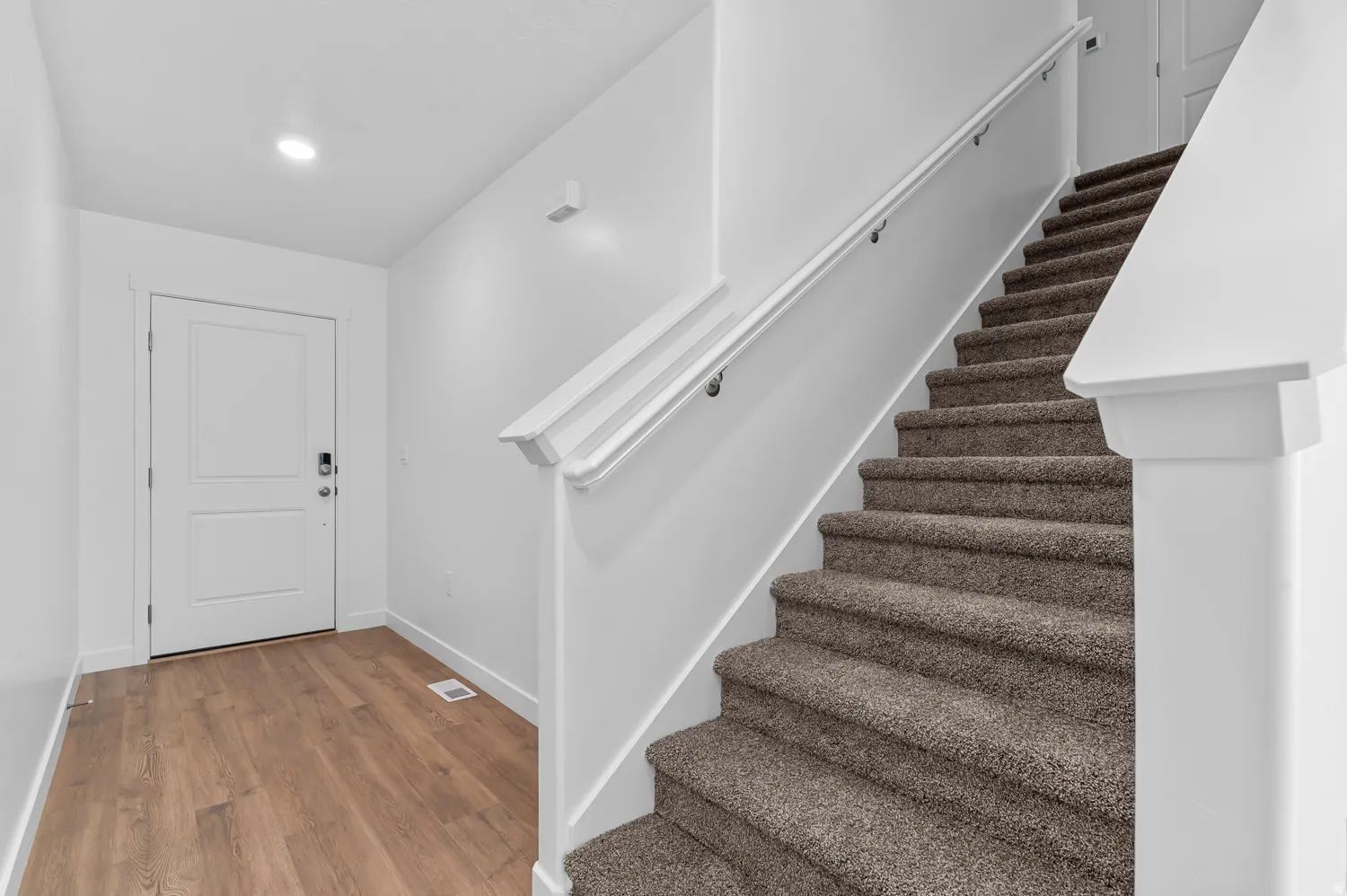 Entryway featuring wood-finish flooring, a white paneled door, and recessed lighting