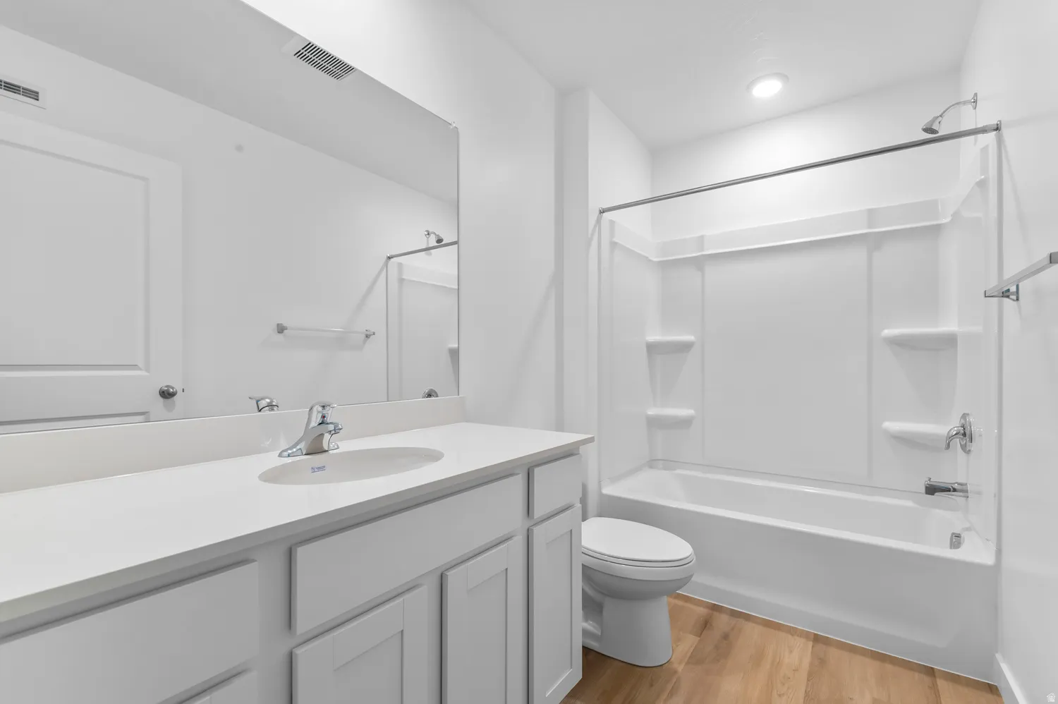 Bathroom featuring a white vanity with an integrated sink, chrome faucet, and expansive mirror
