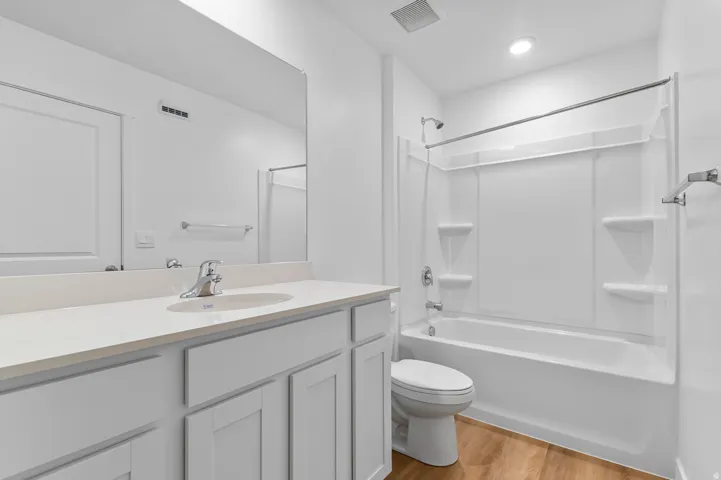 Bright and spa-like primary bathroom featuring a dual-sink vanity with ample storage cabinetry, quartz countertop, and chrome fixtures