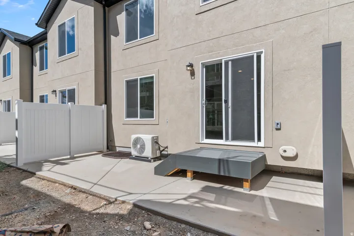 Concrete patio featuring a privacy fence, sliding glass door, and exterior wall sconce