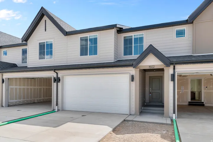 Modern townhouse exterior featuring light-colored siding, dark trim, and a prominent gable roofline