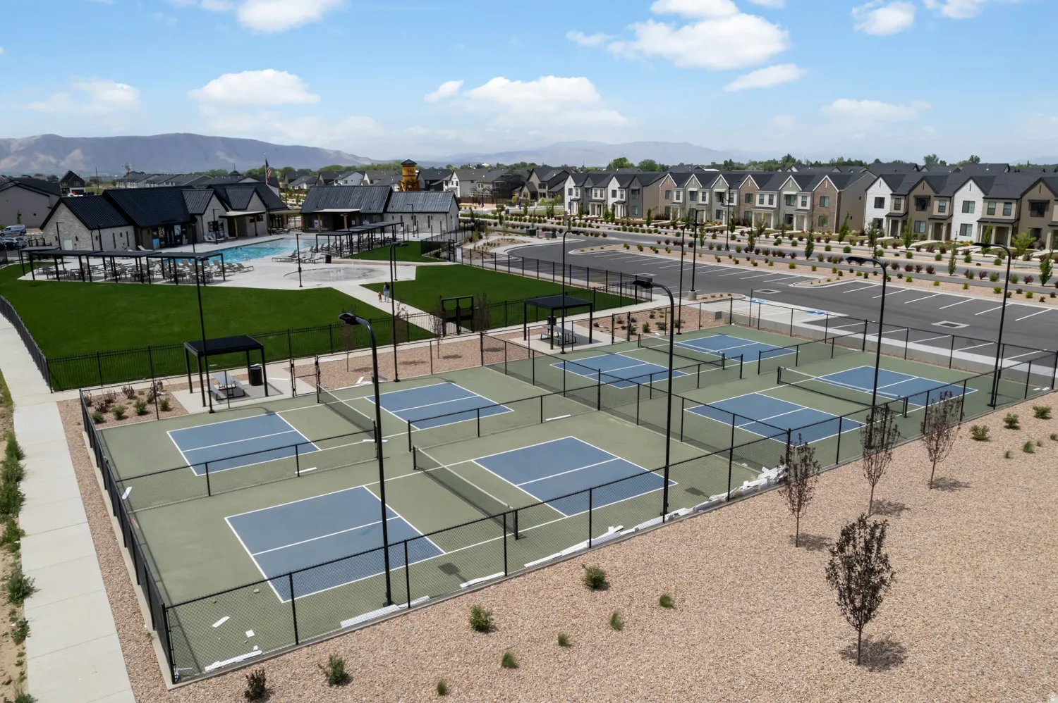 Recreational area featuring multiple fenced courts with light blue and green surfacing, integrated lighting, and covered seating