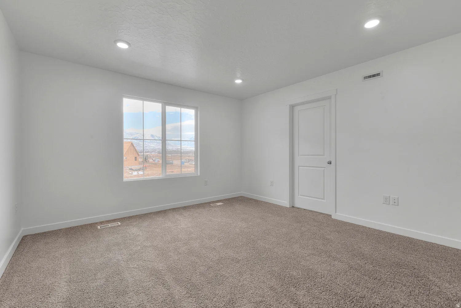 Carpeted room featuring a large window with mountain scenery, recessed ceiling lighting, a contemporary interior door, and white baseboards
