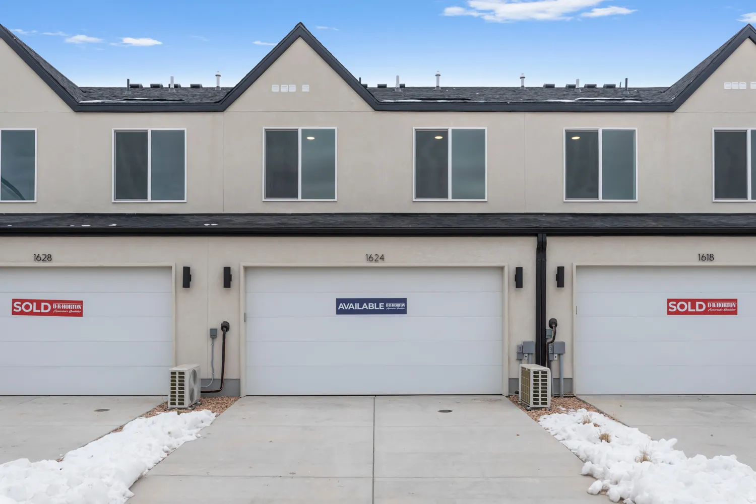 Contemporary townhome facade featuring a light-toned exterior and dark trim