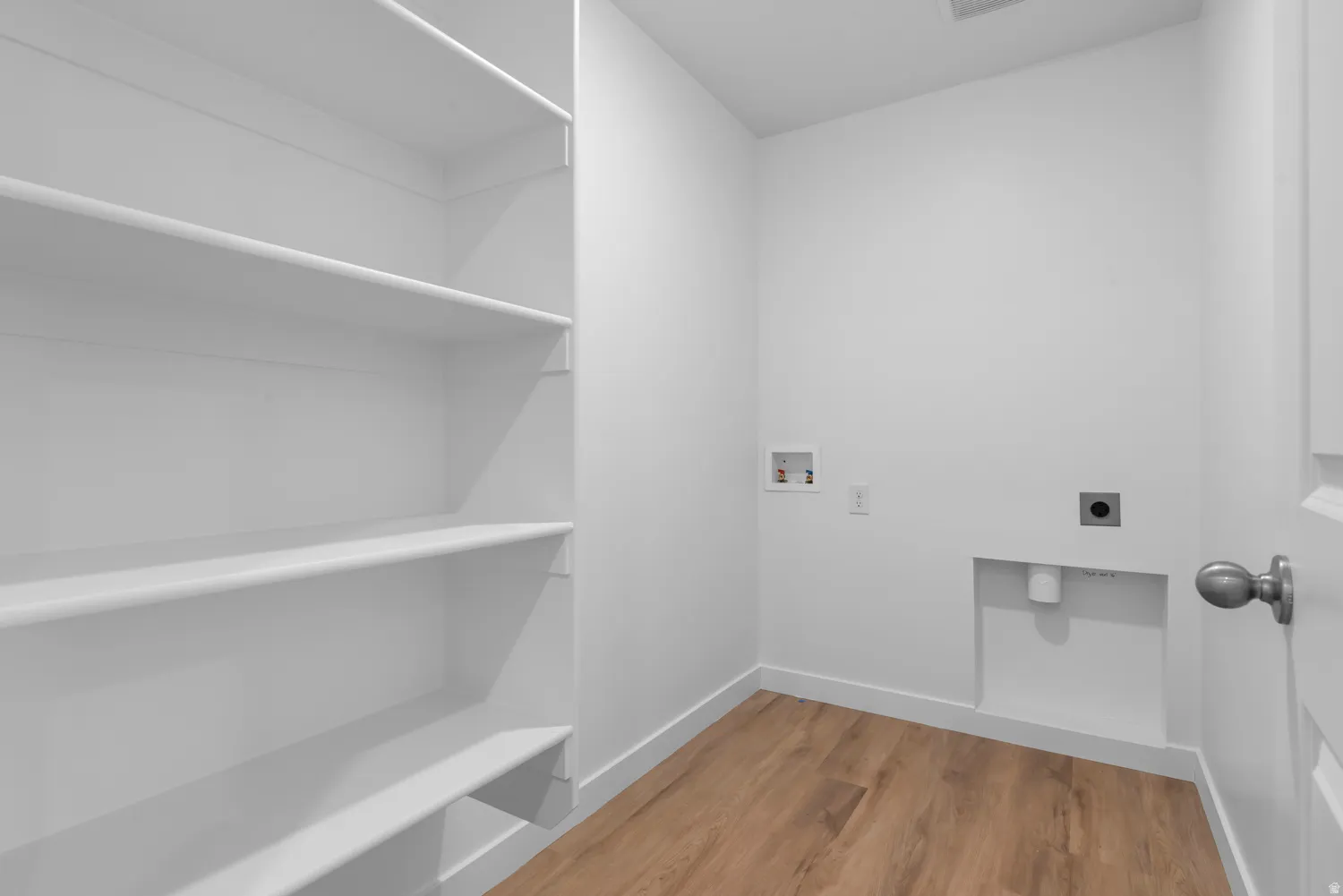 Utility area featuring wood-finish flooring, white walls, and bright overhead lighting