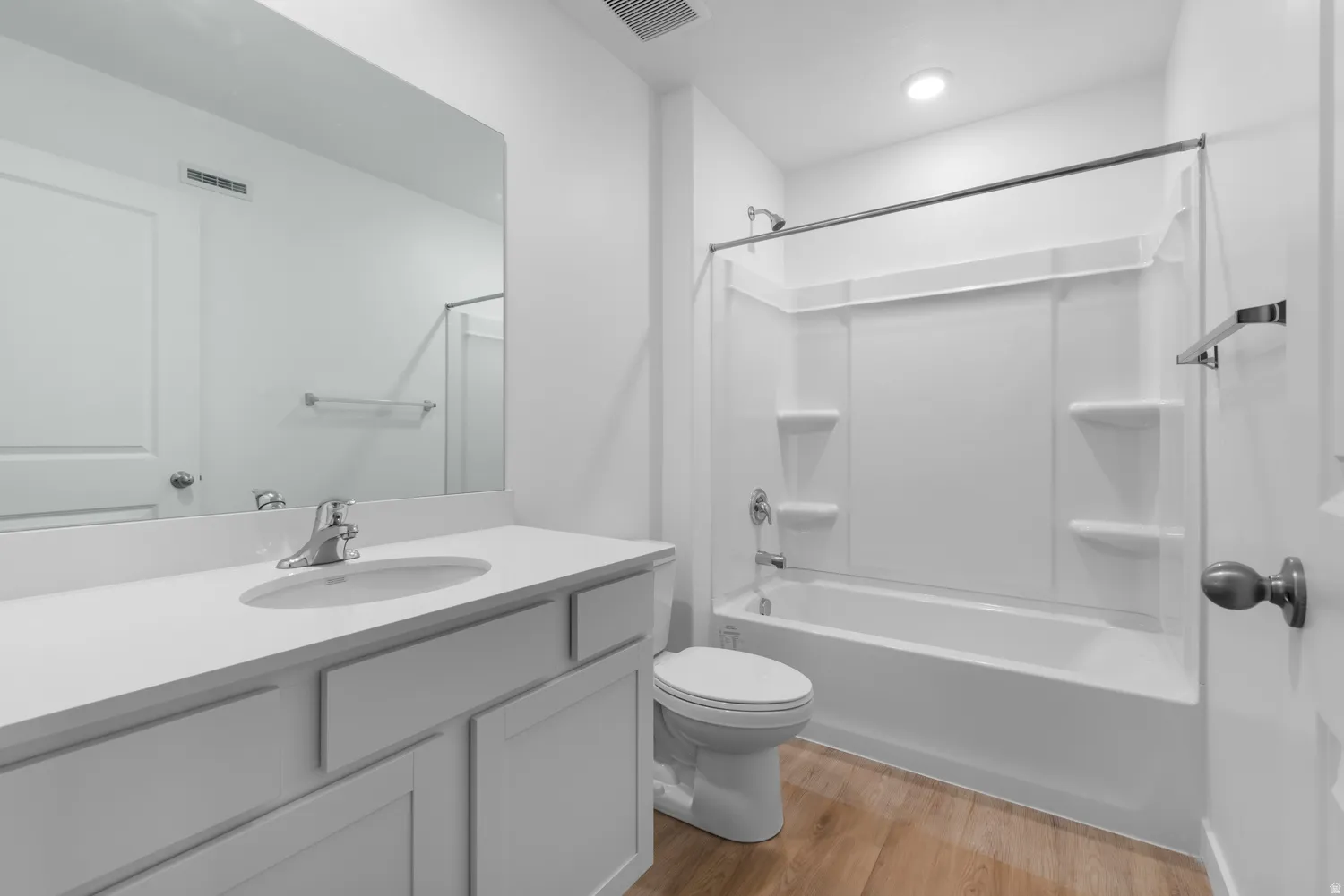 Bathroom featuring a white vanity with an integrated sink, chrome faucet, and a large wall-mounted mirror
