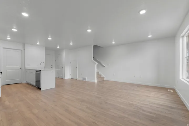 Open-concept living space featuring light wood-finish flooring, recessed lighting, and white walls
