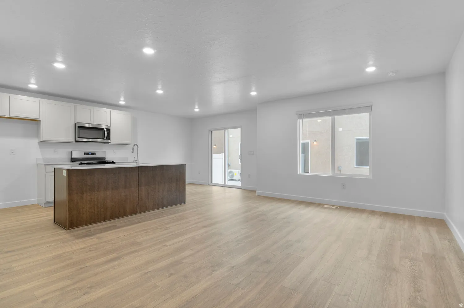 Open-concept living space featuring wood-finish flooring, recessed lighting, and a white color palette