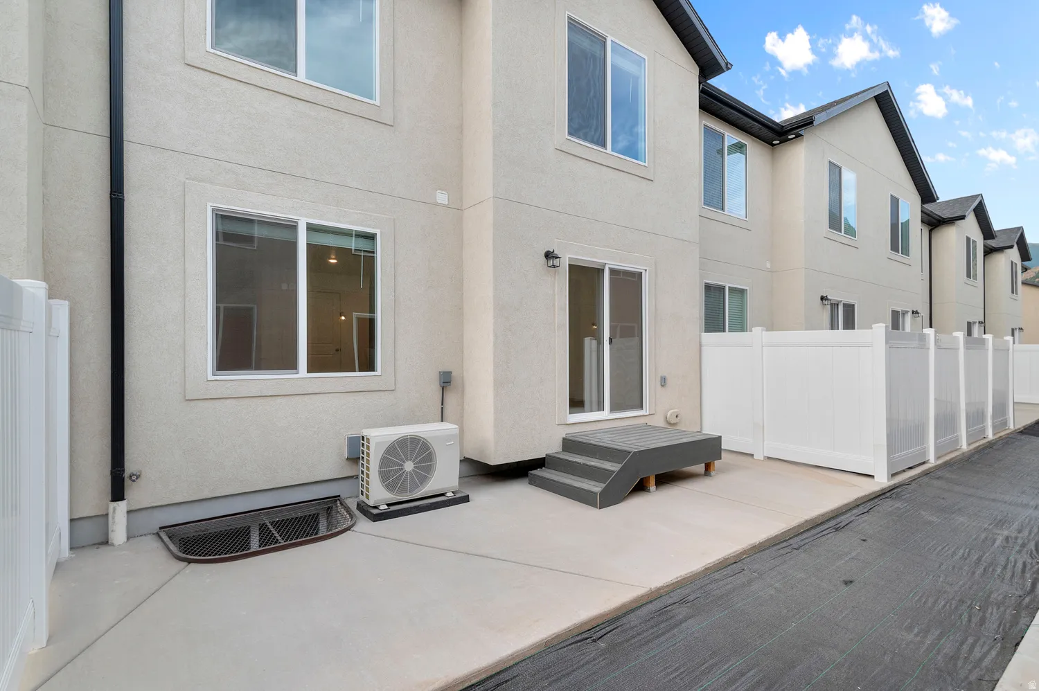 Rear elevation featuring stucco siding and white vinyl fencing