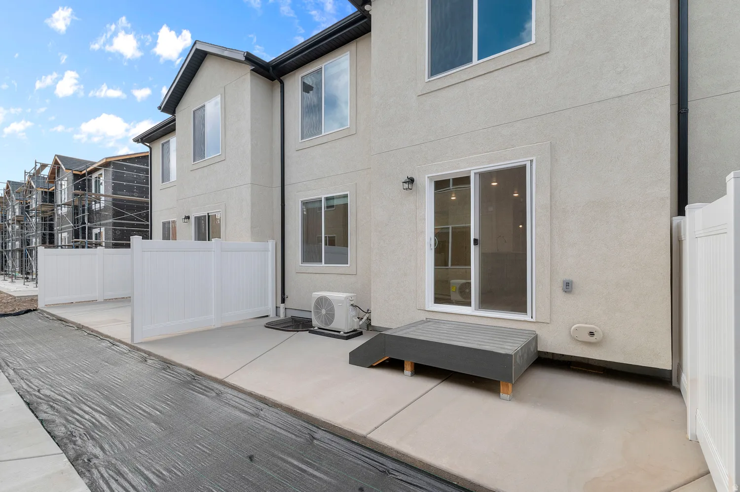 Rear exterior featuring a sliding glass door, private patio space, white vinyl fencing, and an exterior light fixture