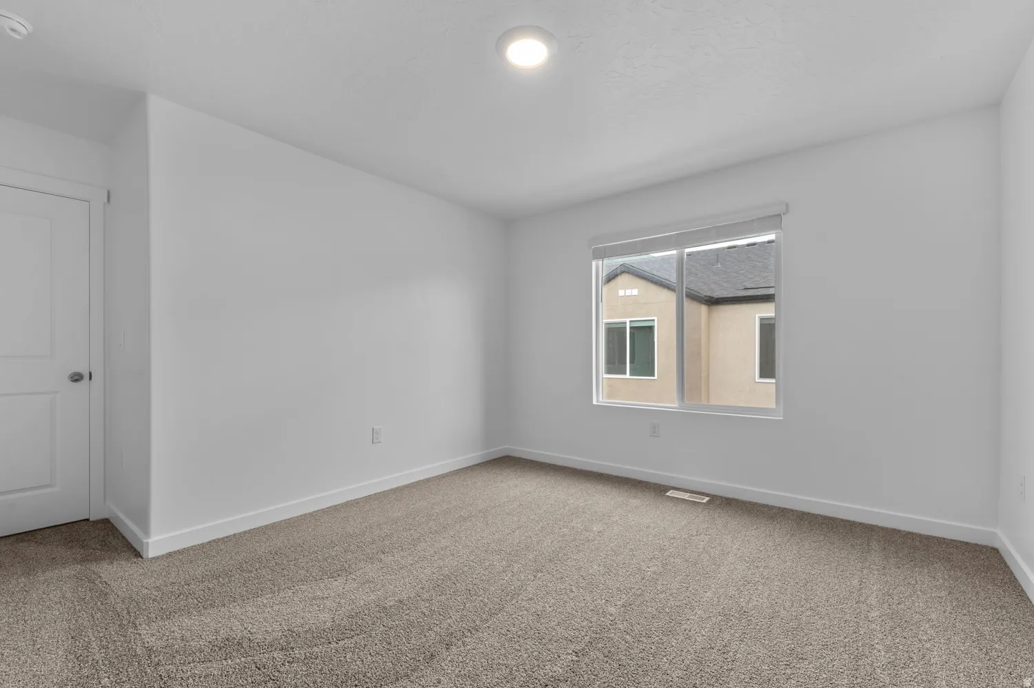 Carpeted room with white walls, a single window, and a white interior door