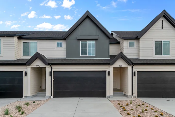 Modern townhome facade featuring light beige siding and dark gray accent panels