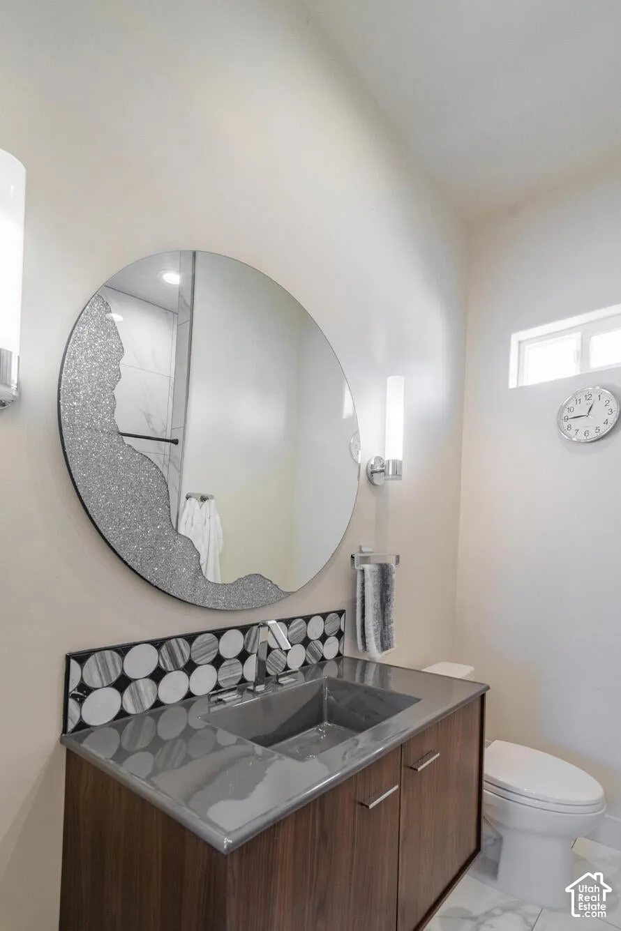 Bathroom featuring a modern floating vanity with a dark wood-finish, integrated gray sink, and a circular mirror with decorative detailing