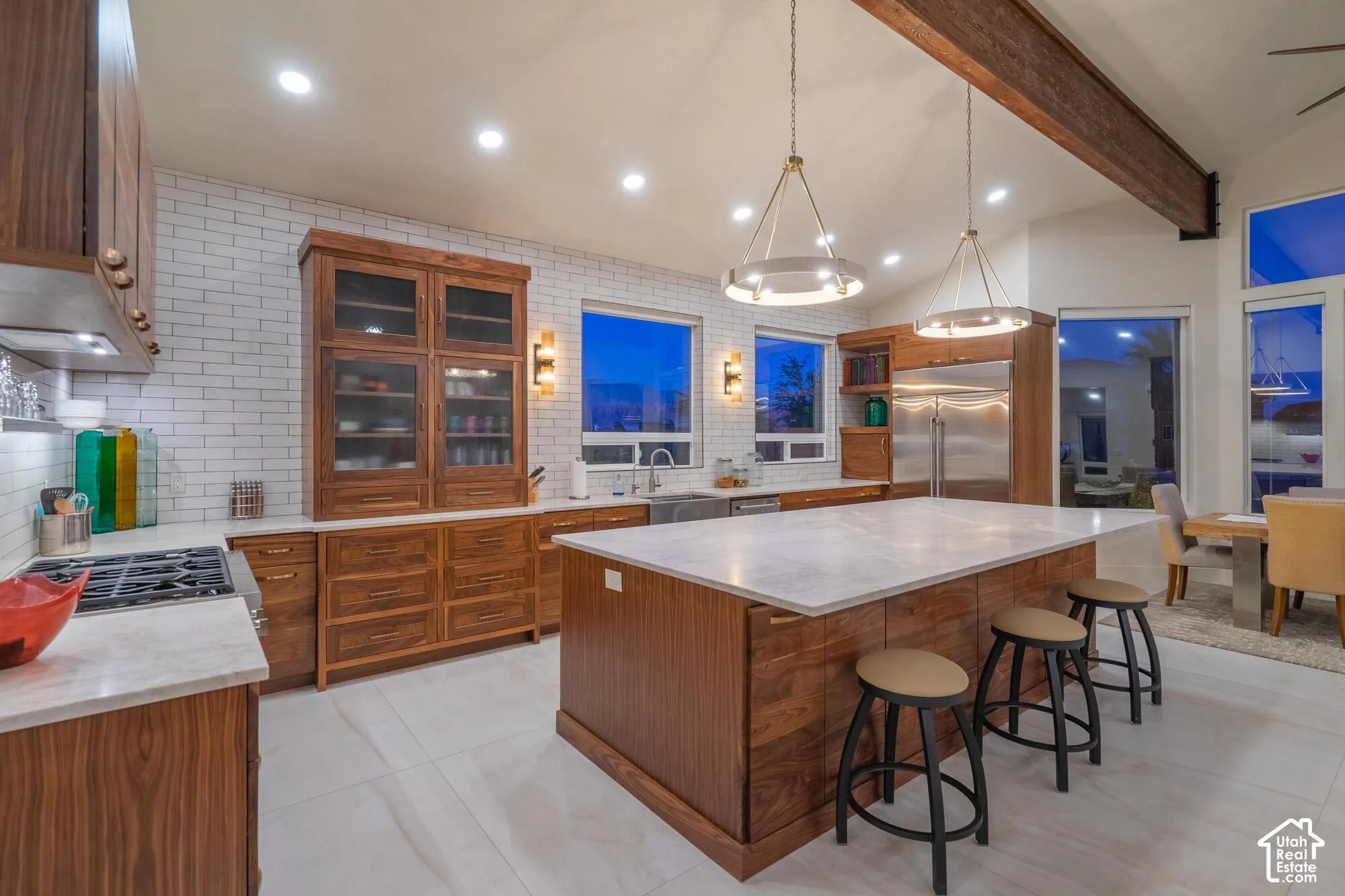 Spacious kitchen featuring a large central island with seating, a gas cooktop, stainless steel appliances, and wood-finish cabinetry