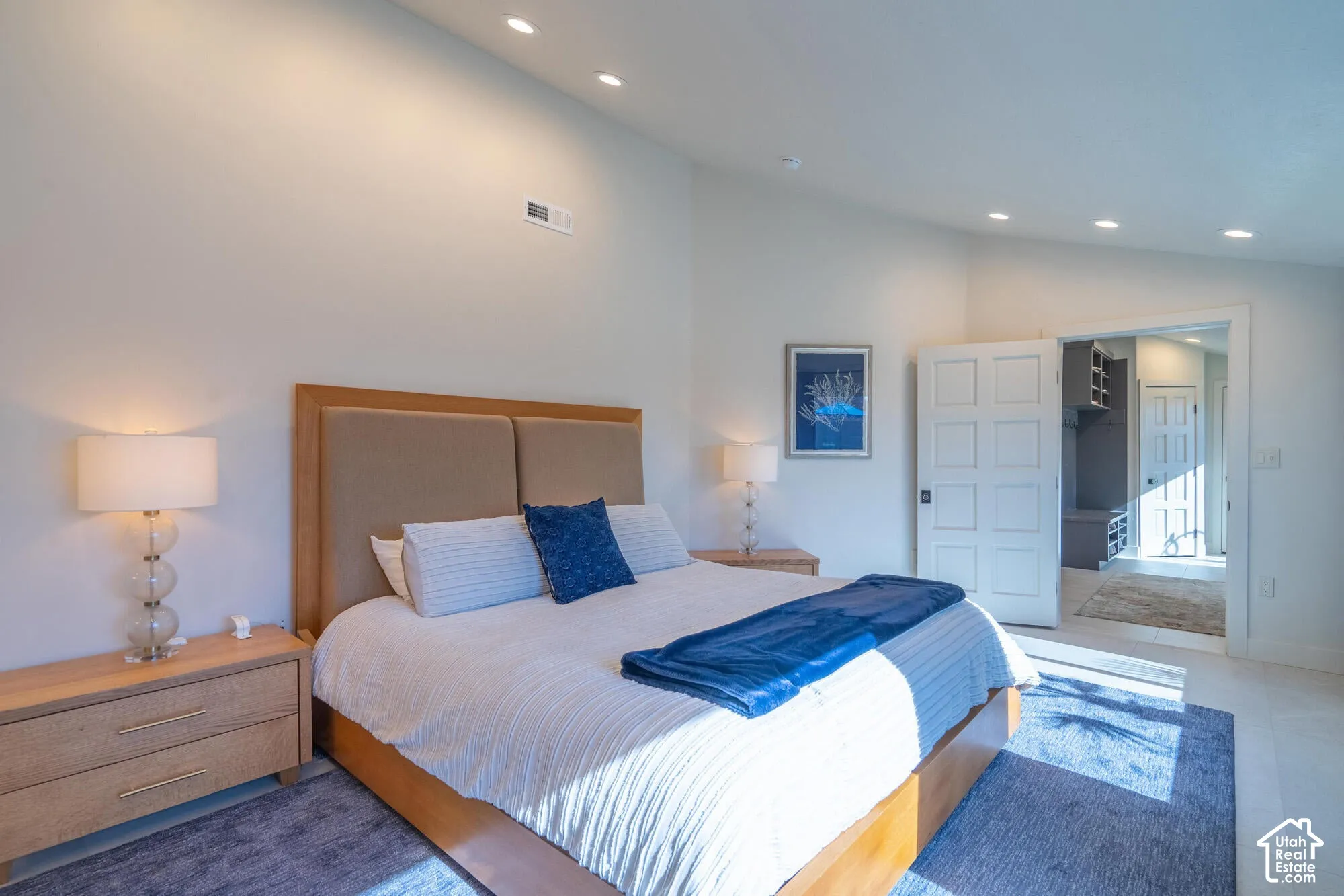 Spacious bedroom featuring light-toned walls, recessed lighting, and a neutral wood-finish flooring