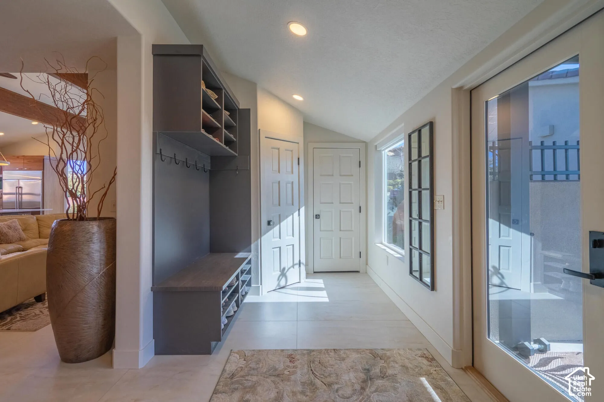 Entryway featuring a built-in mudroom bench with shelving and coat hooks, a glass-paneled door, recessed lighting, and light-tone flooring