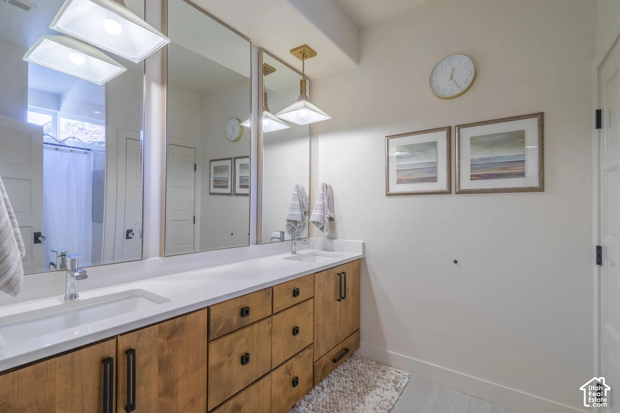 Double vanity featuring white rectangular under-mount sinks, chrome faucets, and a light wood-finish cabinetry base with black hardware