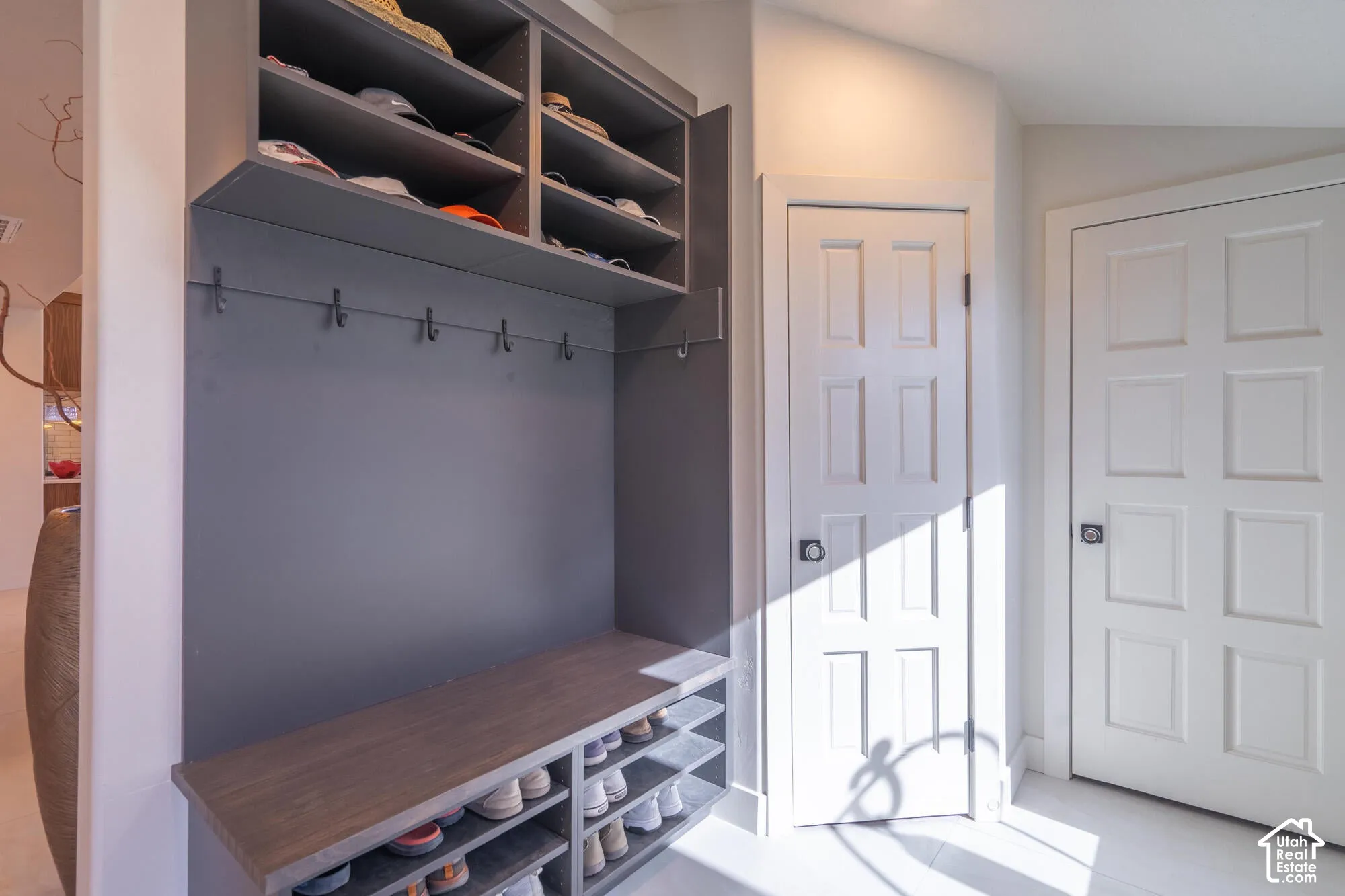 Built-in gray mudroom storage featuring a wood-finish bench, open shelving, and coat hooks