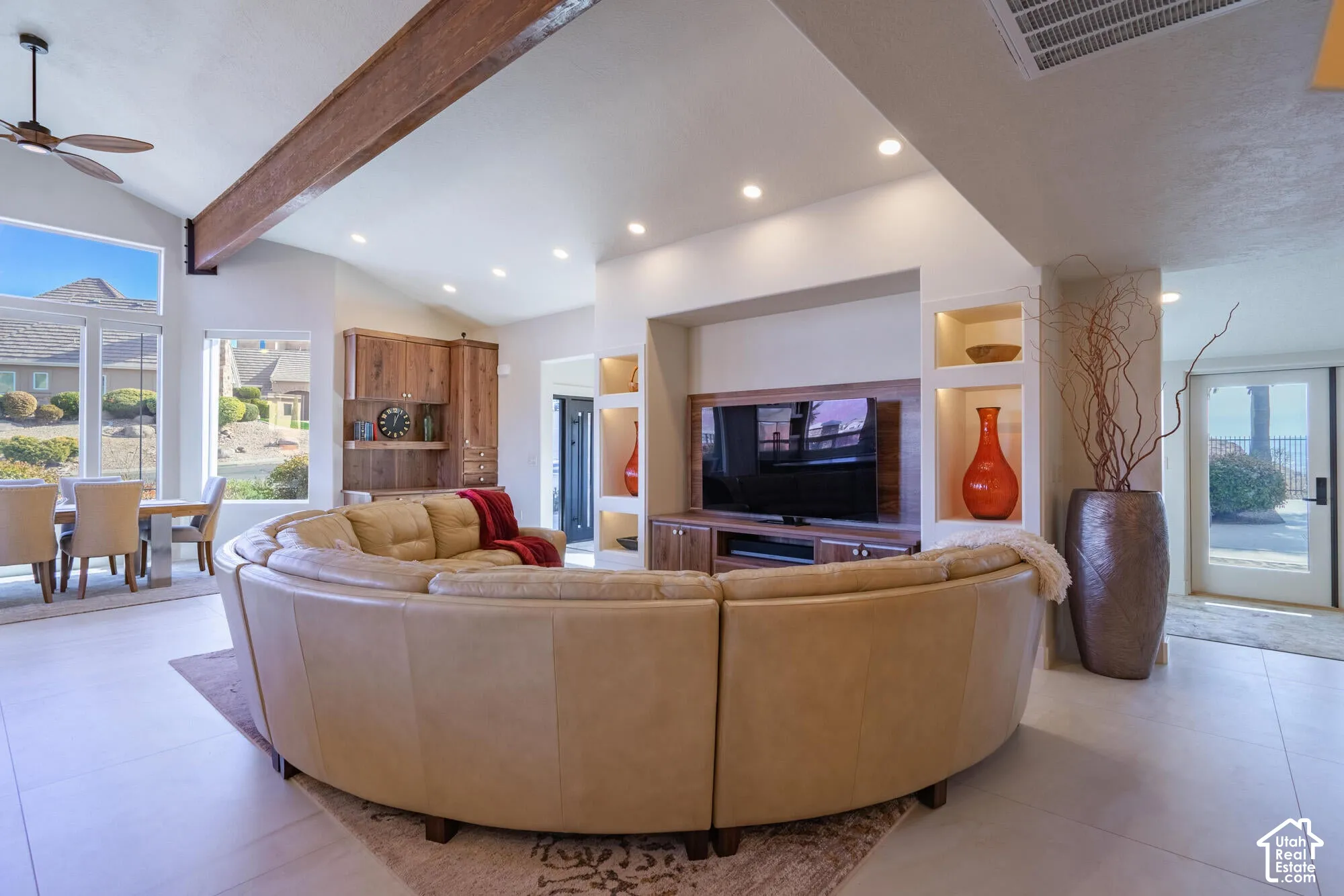 Vaulted ceilings with an exposed beam, recessed lighting, large picture windows, and a built-in media center with illuminated display niches
