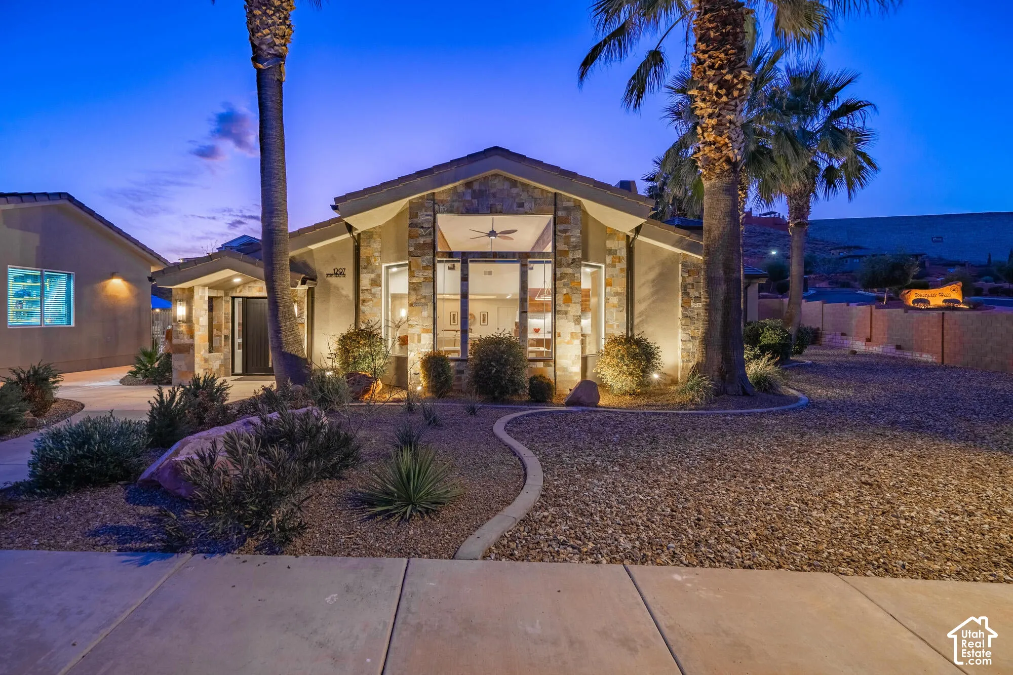 Modern desert-style residence featuring stone veneer accents and a prominent front-facing window wall