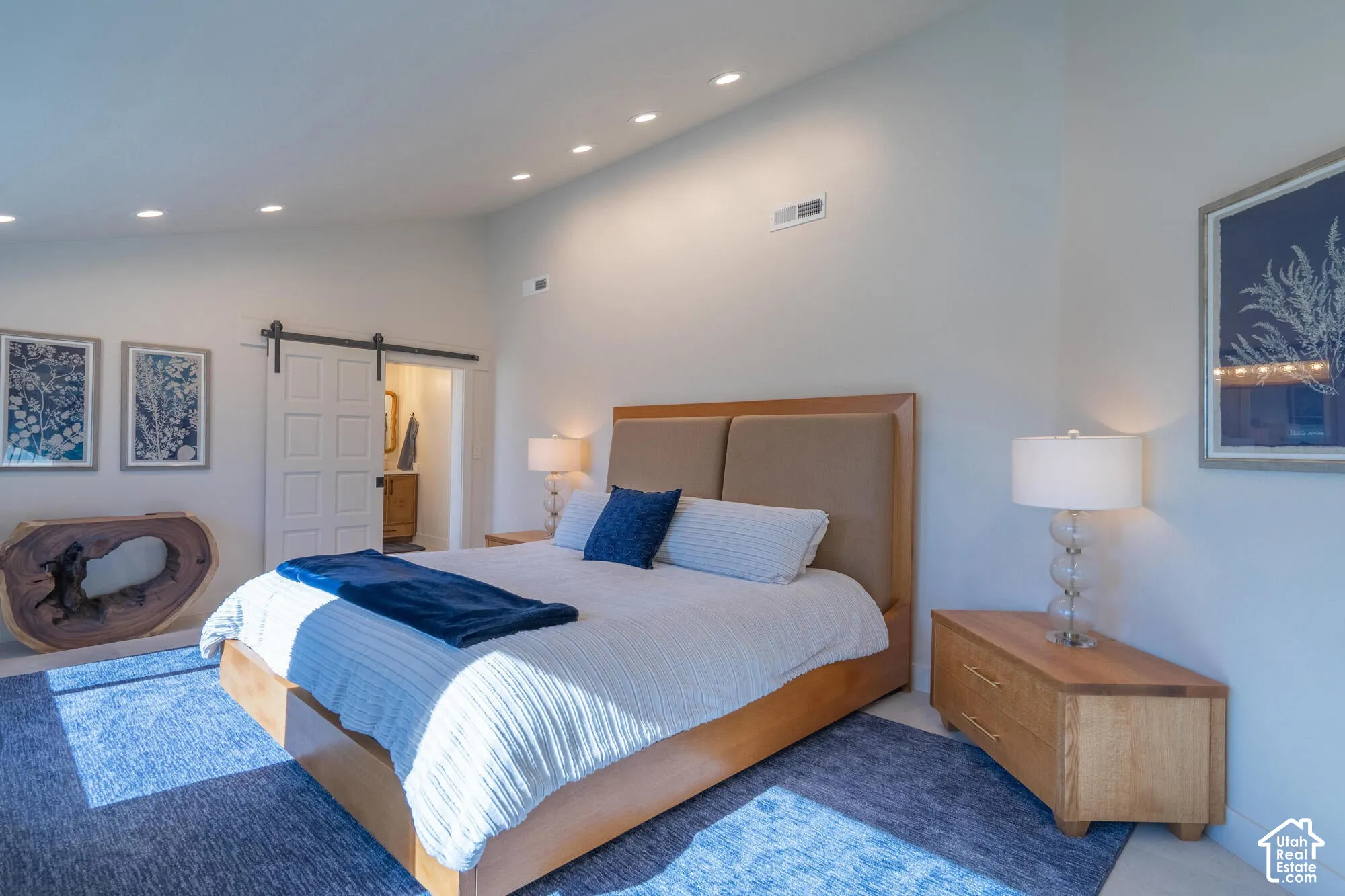 Vaulted ceiling bedroom featuring recessed lighting, a sliding barn door, and light-toned flooring