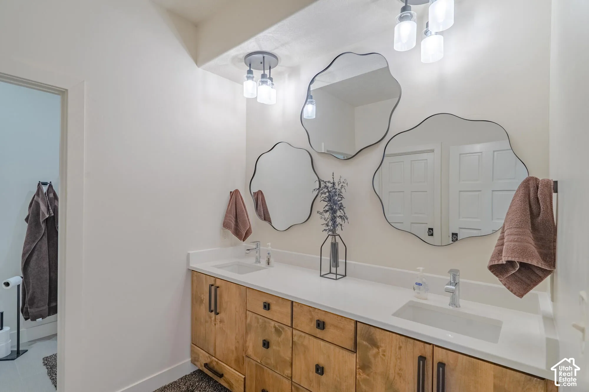 Dual vanity with a light wood-finish cabinetry, white countertops, and integrated rectangular sinks