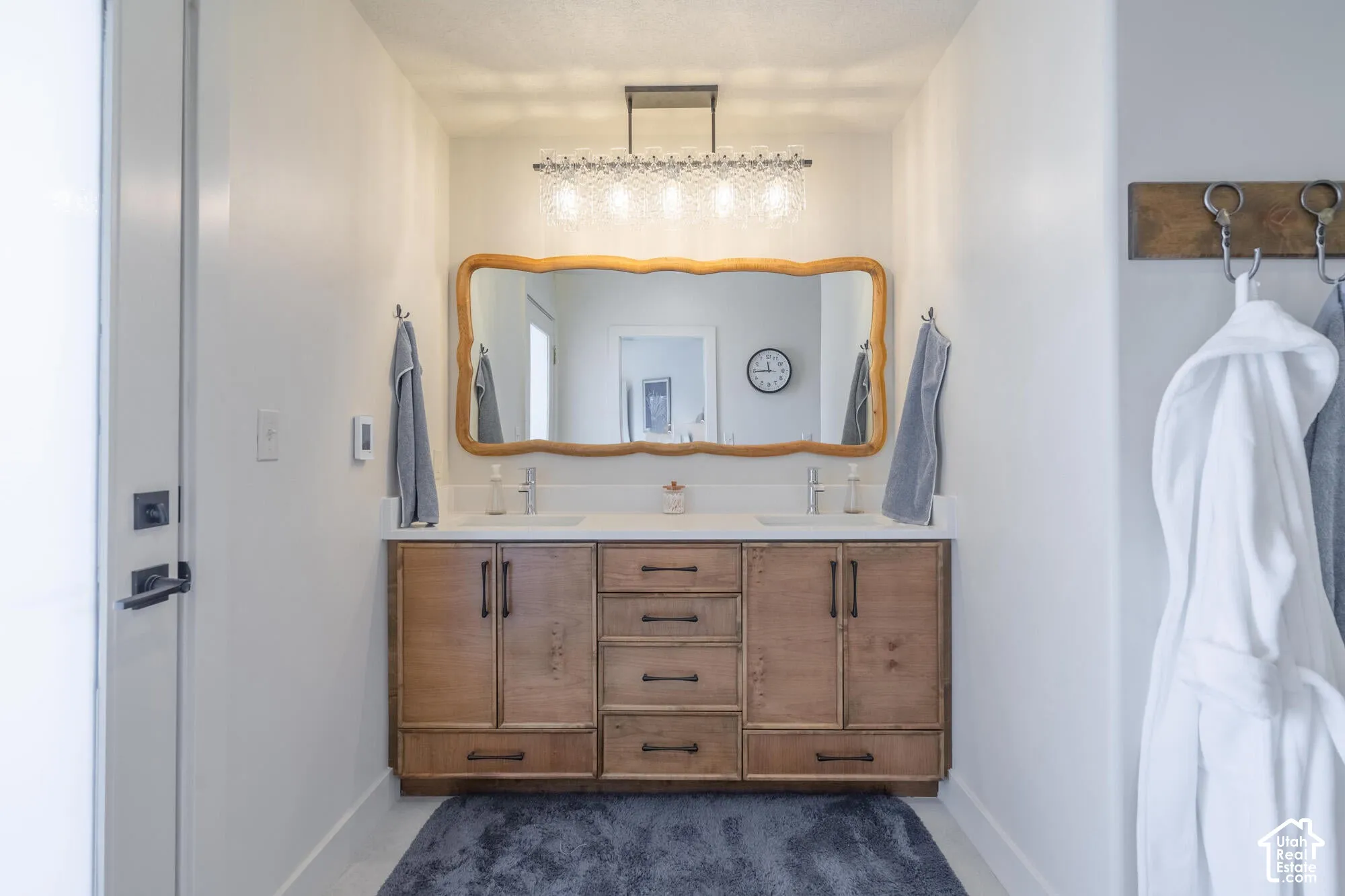 Double vanity with light wood cabinetry, white countertop, and dual undermount sinks