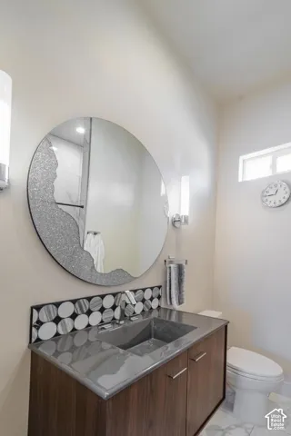 Bathroom featuring a modern floating vanity with a dark wood-finish, integrated gray sink, and a circular mirror with decorative detailing