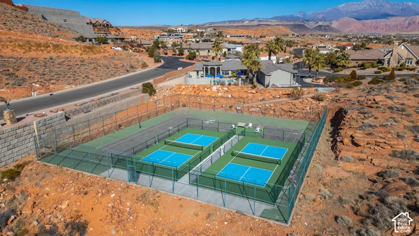 Recreational complex featuring two enclosed pickleball courts and an additional tennis court