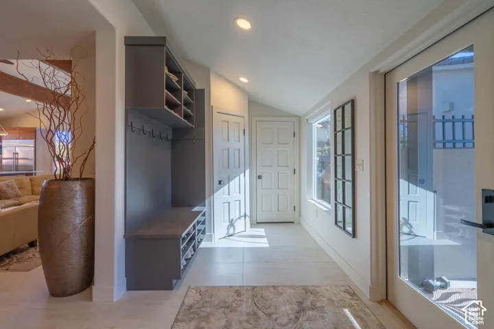 Entryway featuring a built-in mudroom bench with shelving and coat hooks, a glass-paneled door, recessed lighting, and light-tone flooring