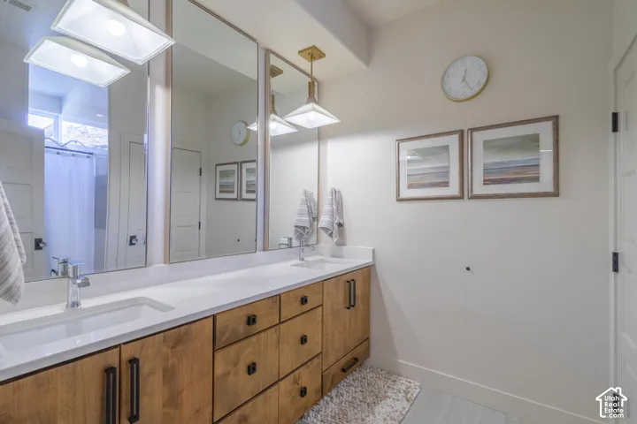 Double vanity featuring white rectangular under-mount sinks, chrome faucets, and a light wood-finish cabinetry base with black hardware