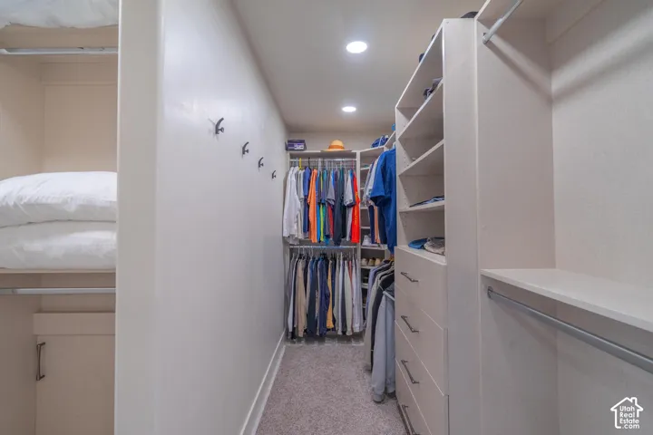 Walk-in closet featuring extensive built-in shelving, multiple hanging rods, integrated drawers, and recessed lighting