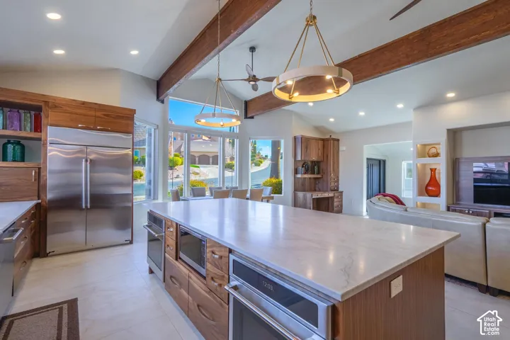 Spacious kitchen featuring a large central island with a light-toned countertop, integrated oven, and microwave