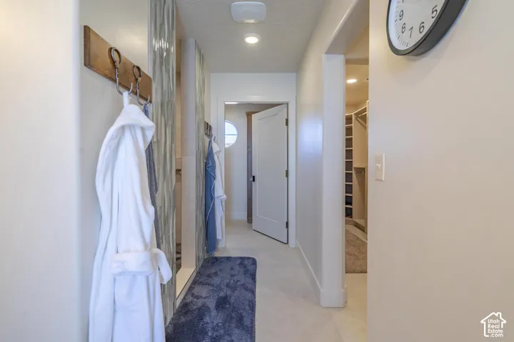 Hallway featuring recessed lighting, light-toned walls, and a built-in wall-mounted coat rack