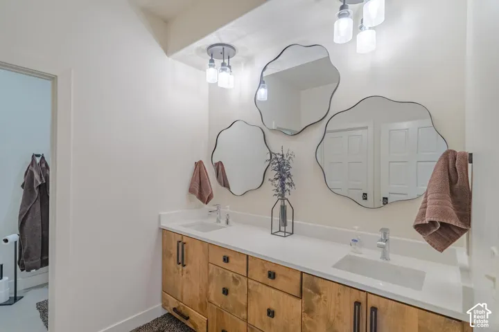 Dual vanity with a light wood-finish cabinetry, white countertops, and integrated rectangular sinks