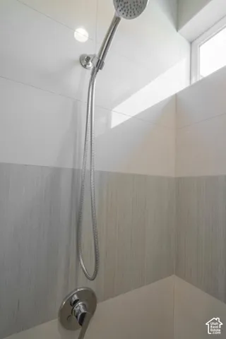 Shower with chrome handheld showerhead and wall-mounted controls
