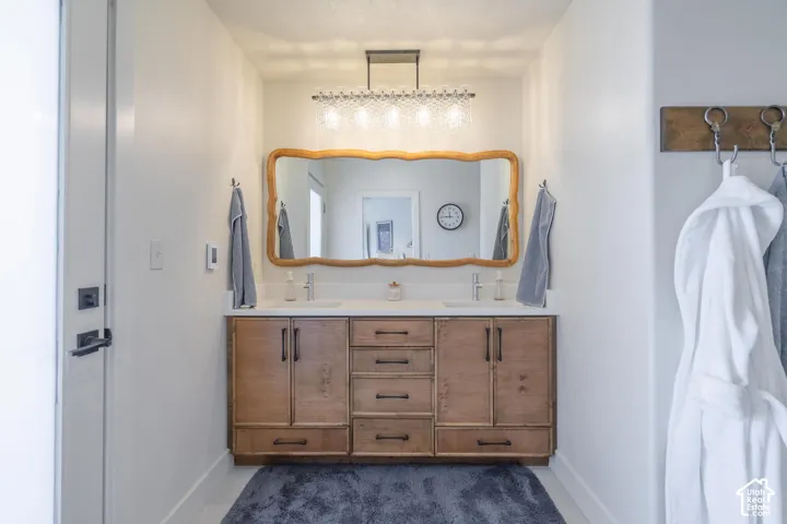Double vanity with light wood cabinetry, white countertop, and dual undermount sinks