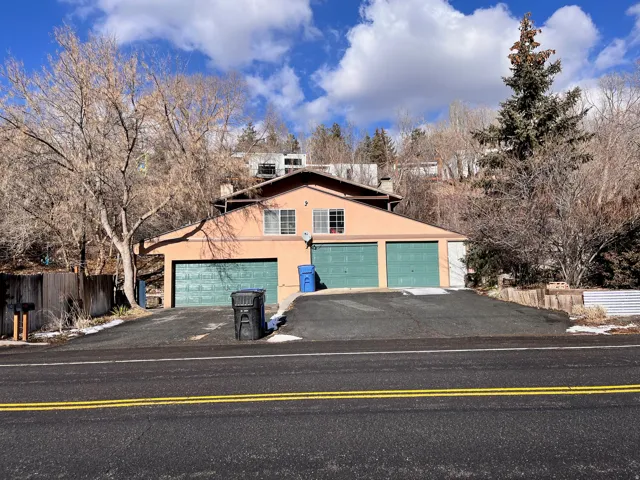 Multi-level stucco exterior with a brown roof and a three-car garage