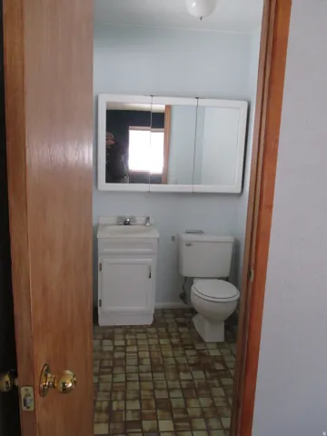 West Side - 1/2 Bathroom featuring a white vanity with integrated sink, a matching white toilet, and a medicine cabinet with multiple mirrored doors