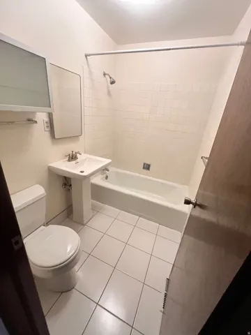 East Side - Bathroom featuring white square floor tiles, a pedestal sink, and a combination shower-tub with white subway-style wall tiles