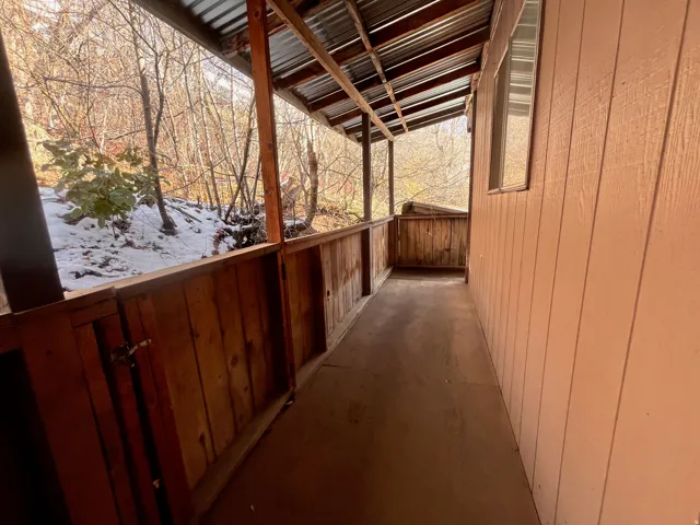 East Side - Small back Covered deck featuring a corrugated metal roof, wood support beams, and natural wood railings