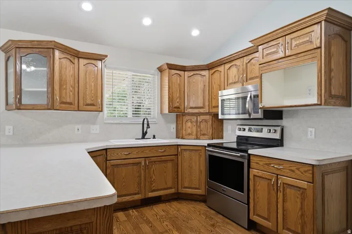 Kitchen featuring wood cabinetry, light countertops, and wood-finish flooring