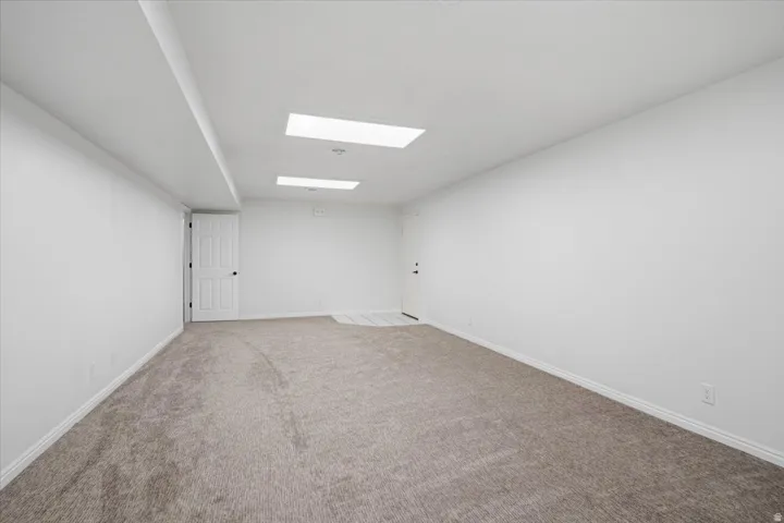 Spacious room with new carpet, white walls, recessed lighting, and a white paneled door