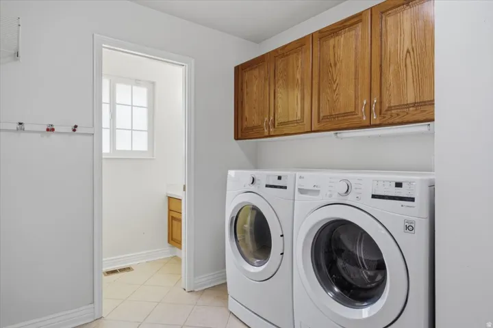Laundry area featuring overhead wood cabinetry and tiled flooring