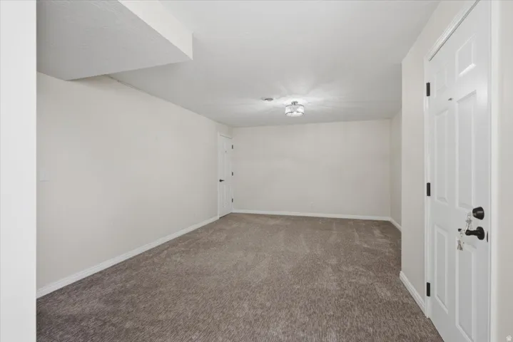 Spacious room featuring plush carpeting, light-toned walls, and a contemporary ceiling light fixture