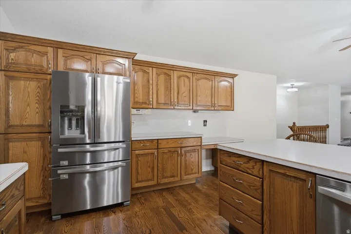 Kitchen featuring extensive wood cabinetry, stainless steel refrigerator, white countertops, and wood-finish flooring