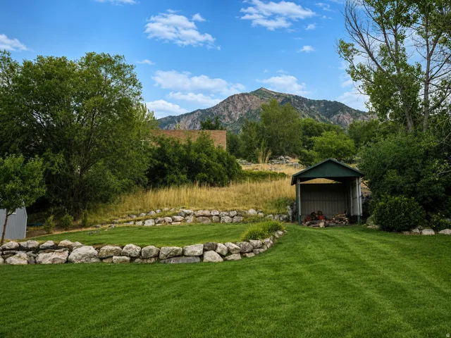 Expansive lawn area featuring a stone retaining wall and a storage shed