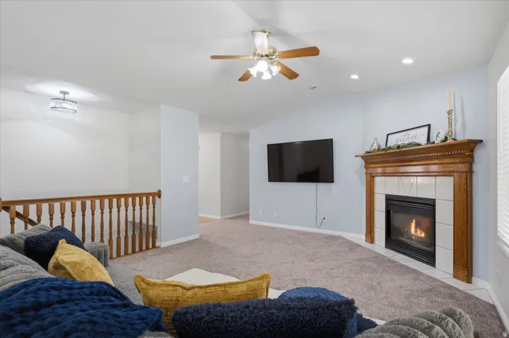 Living area featuring a classic wood mantel fireplace with a tiled surround, vaulted ceilings, and recessed lighting