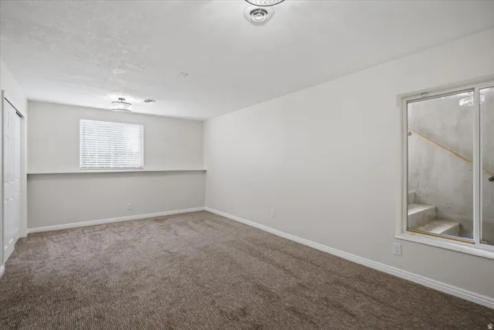 Spacious room featuring neutral carpeting, white walls, and a window with blinds