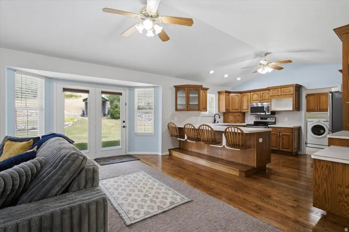 Open-concept living space featuring wood-finish flooring, vaulted ceilings, and ceiling fans